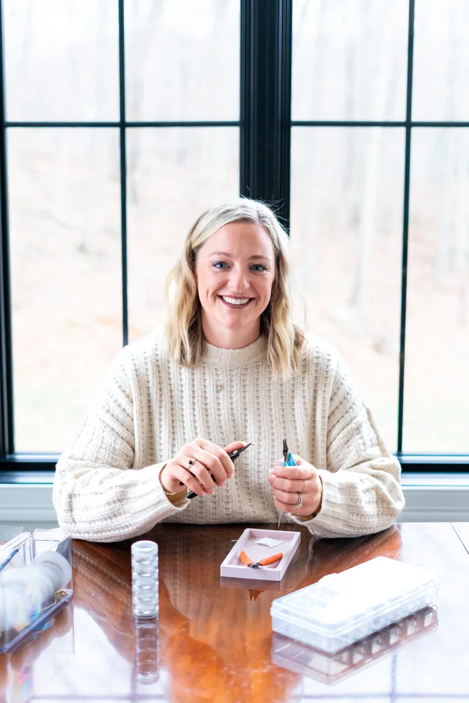 Becky smiling at her worktable as she makes jewelry