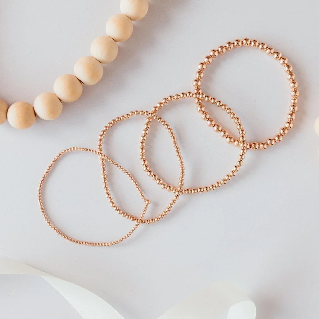 Four rose gold beaded stretch bracelets in different bead sizes