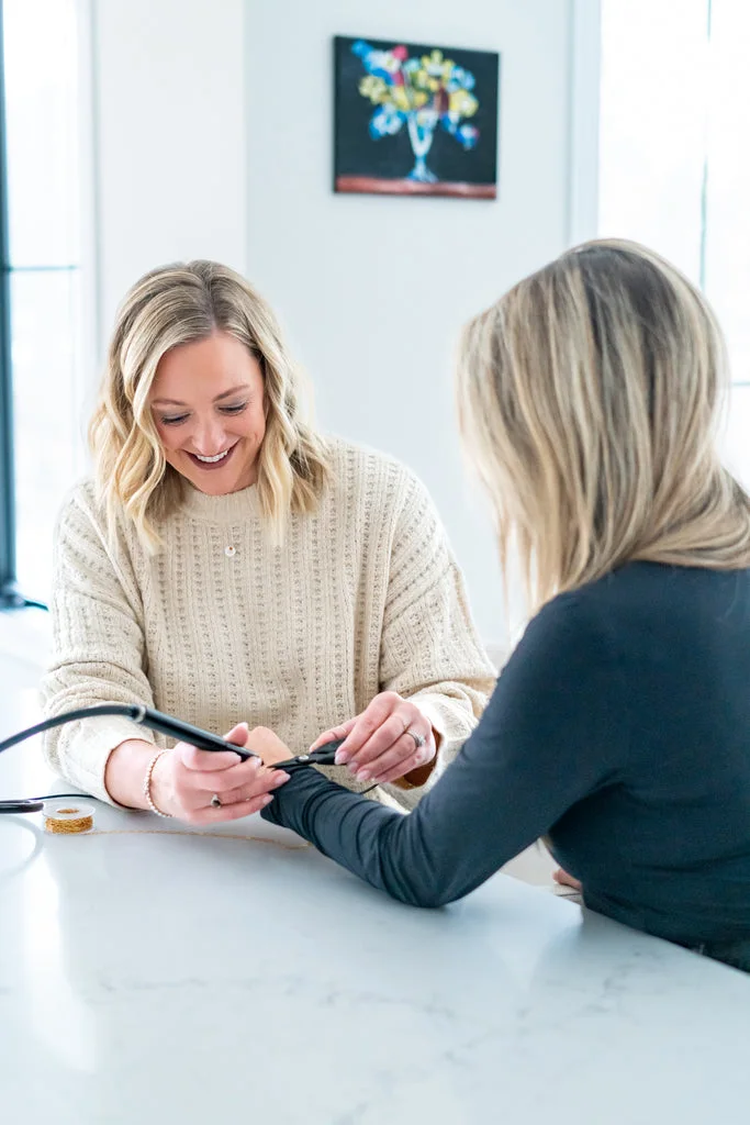 Becky fitting permanent jewelry on a customer's wrist